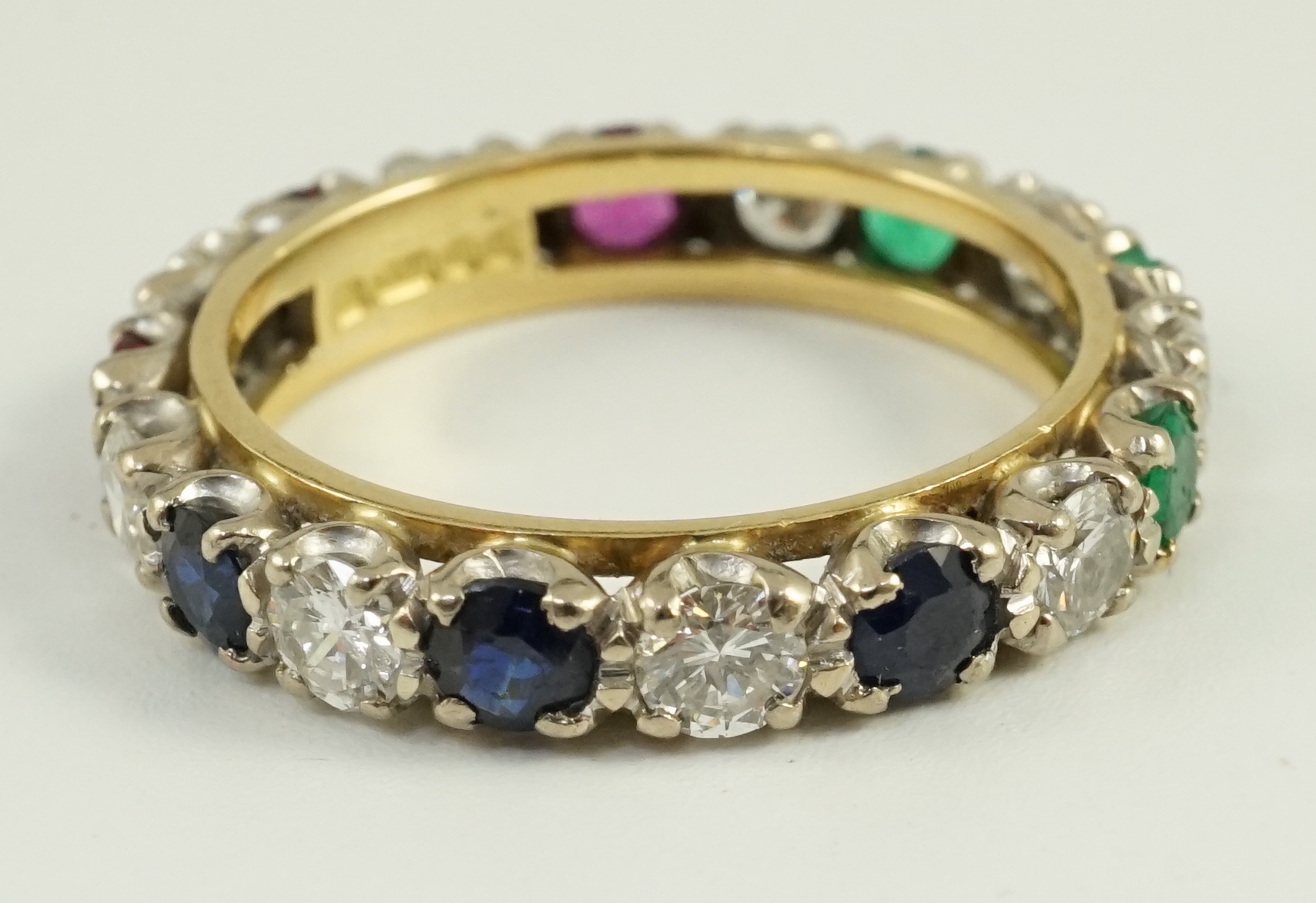 A modern 18ct gold, ruby, sapphire, emerald and diamond set full eternity ring